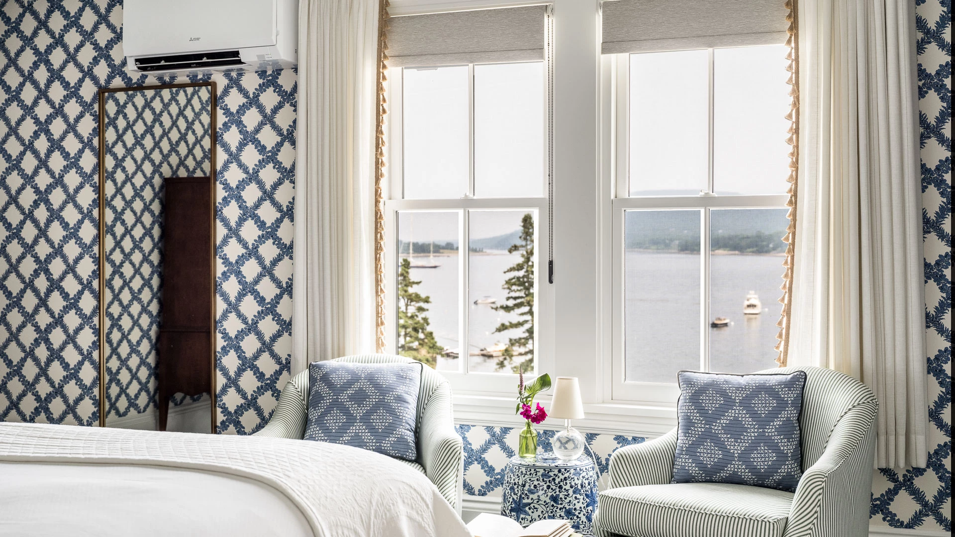 a bedroom with a bed and chairs by a window