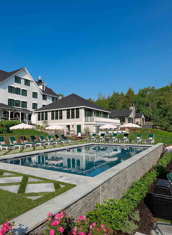 a pool with chairs and a building in the background