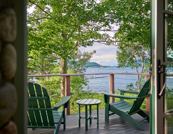 a deck with chairs and a table overlooking water