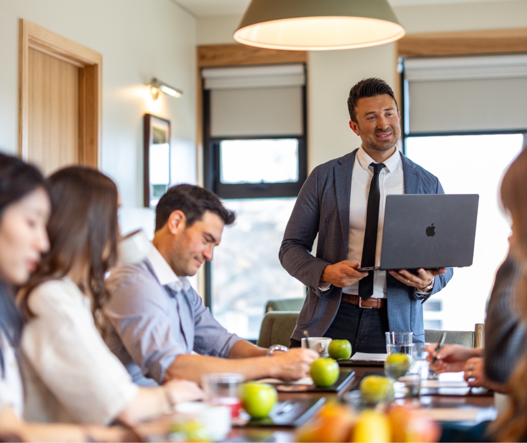 a man holding a laptop and standing next to a group of people