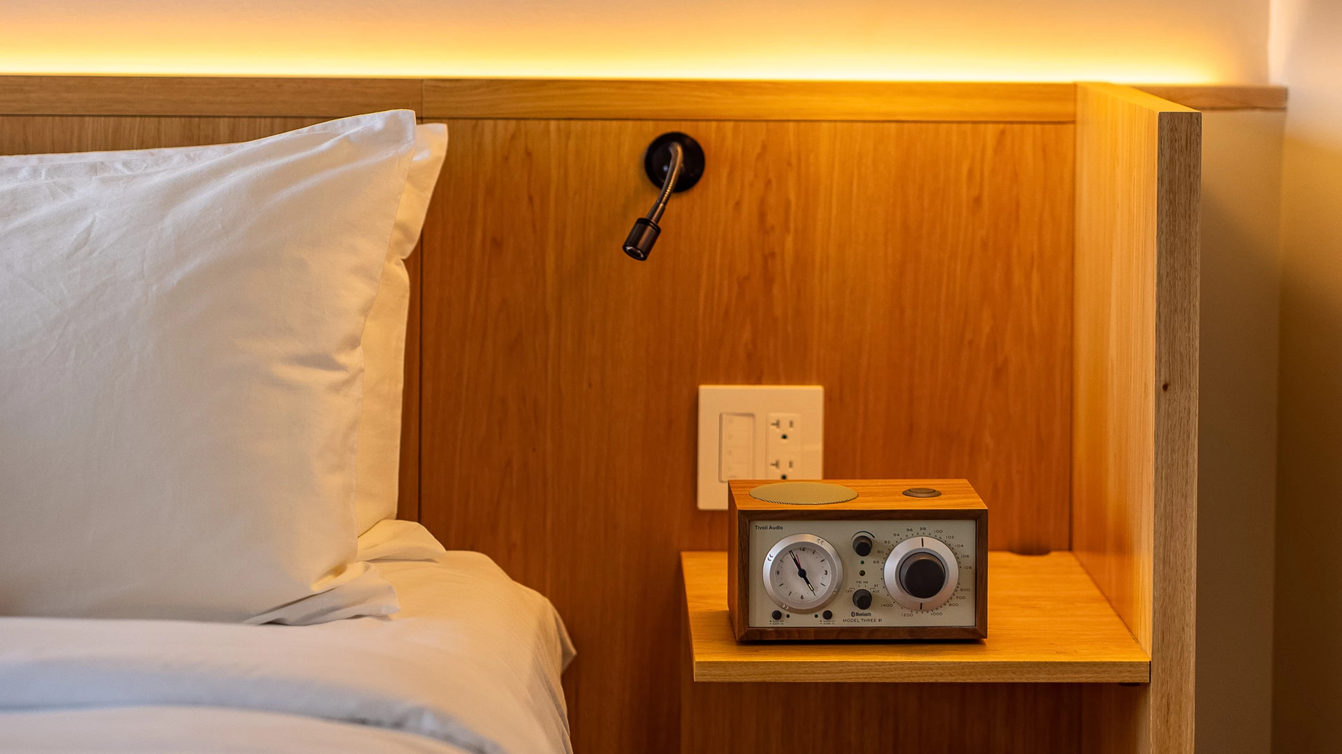 a clock on a table next to a bed