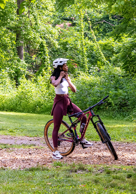 a woman wearing a helmet and holding a bicycle