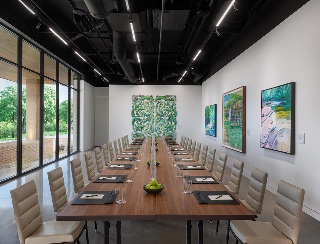 a long table with chairs and art on the wall