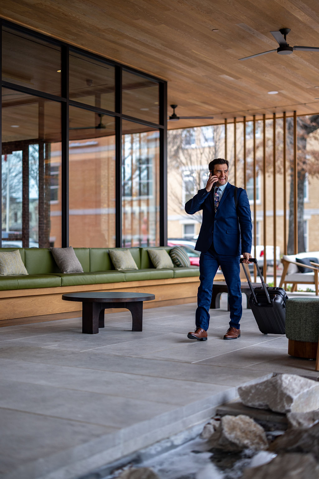 a man in a suit holding a suitcase and talking on a cell phone