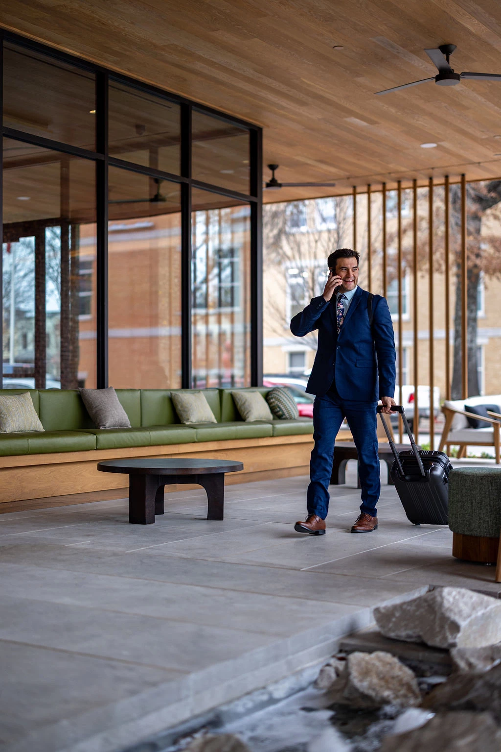 a man in a suit holding a suitcase and talking on a cell phone