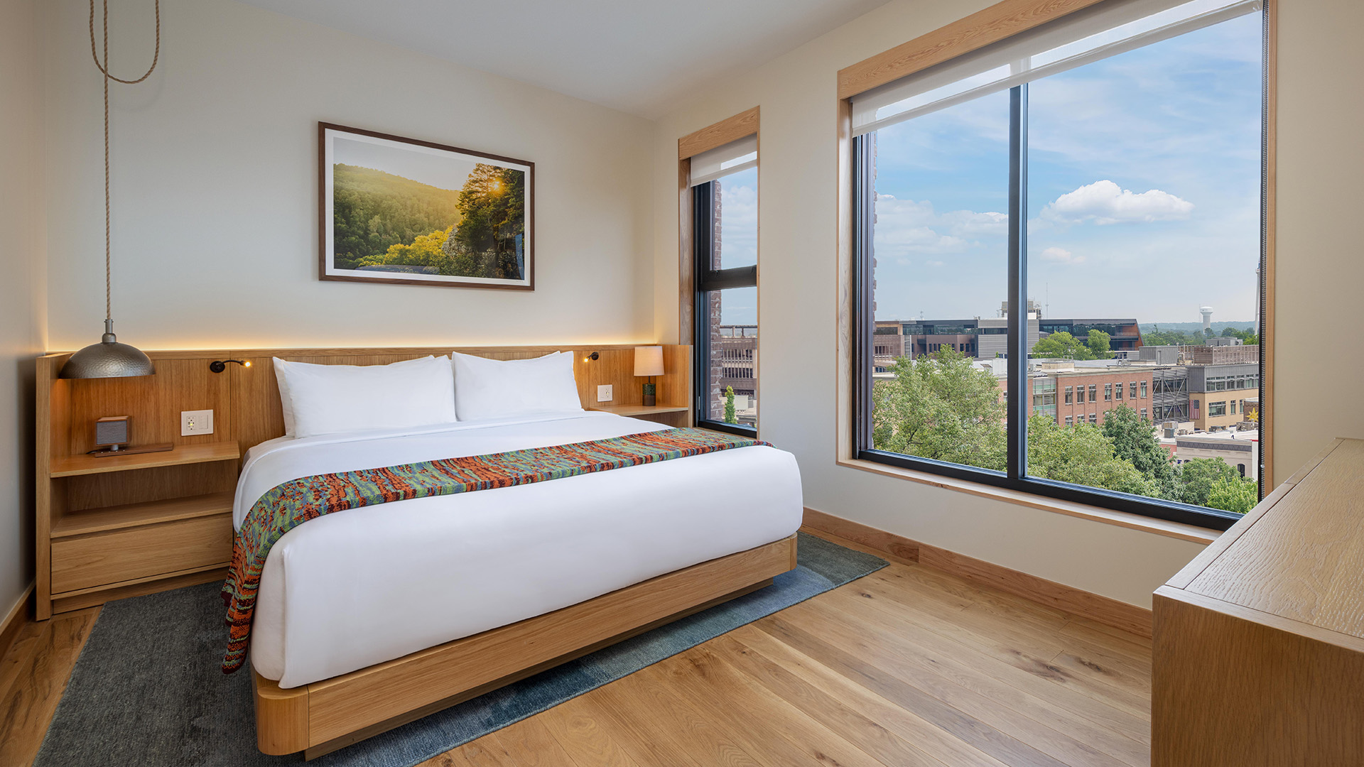 a bed with a colorful blanket in a room with large windows