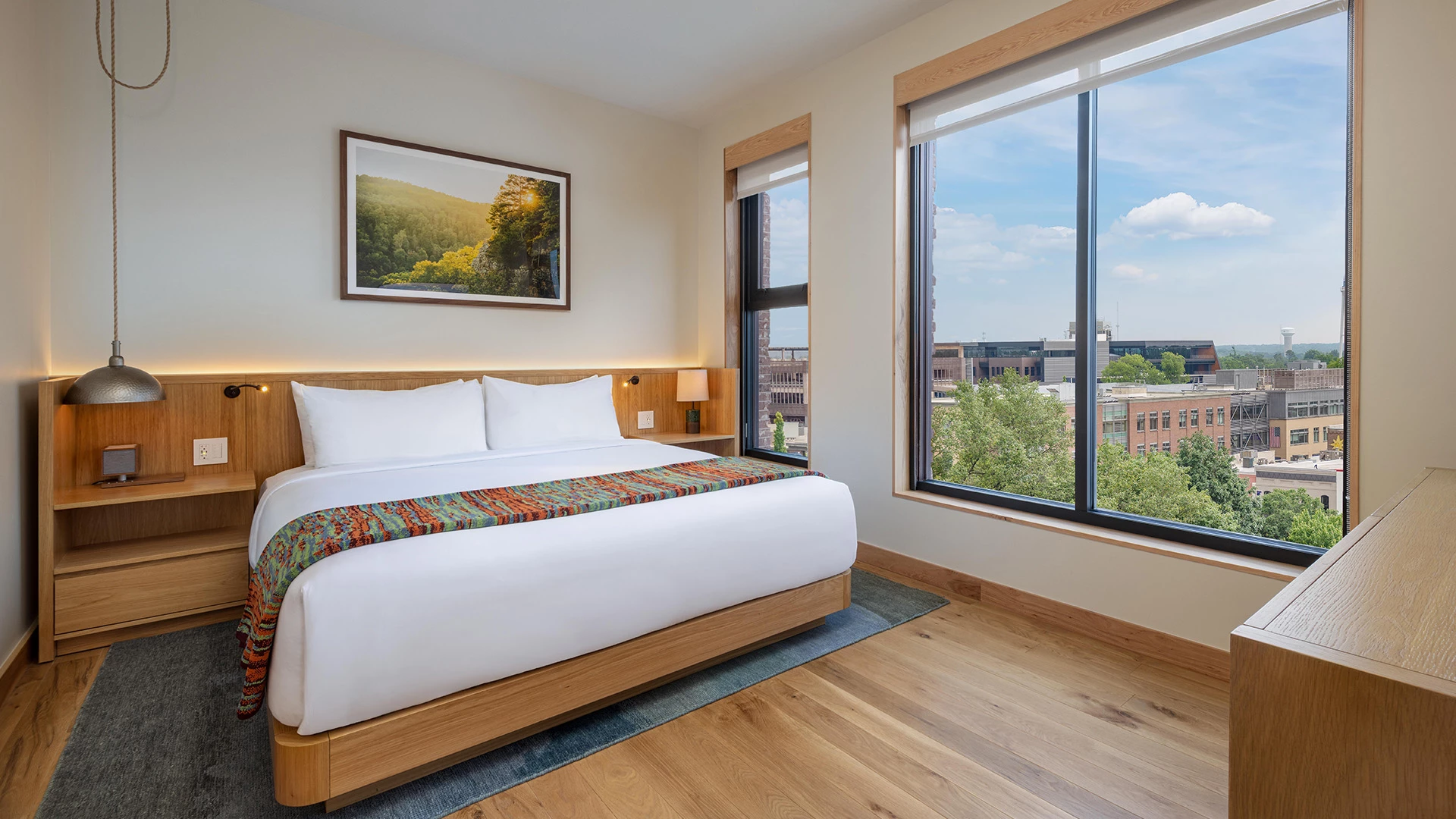 a bed with a colorful blanket in a room with large windows