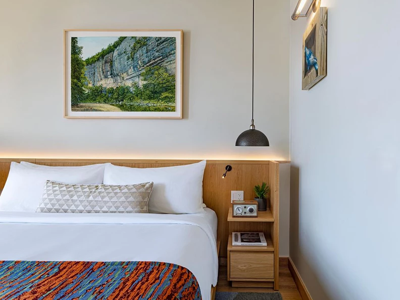 a bed with a wood headboard and a framed picture on the wall