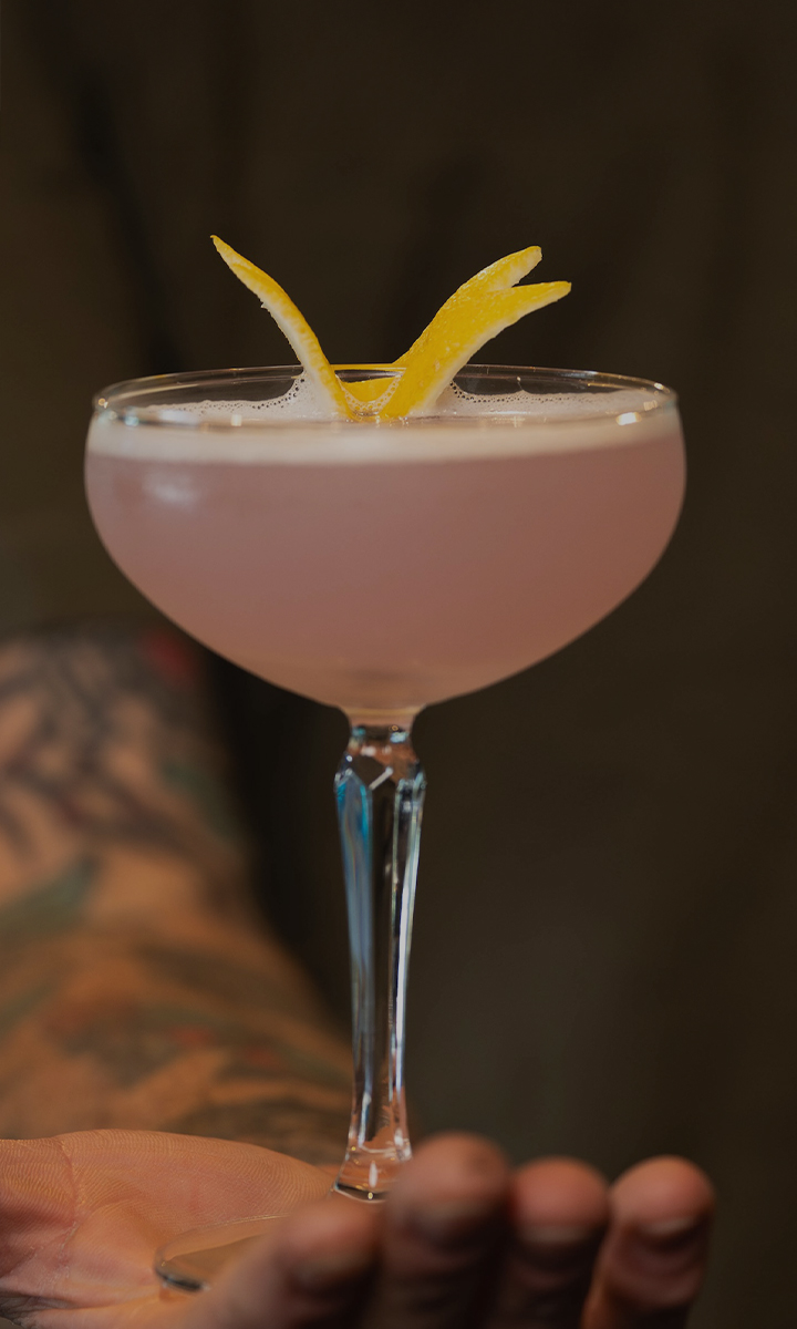 a pink drink with a lemon peel in it