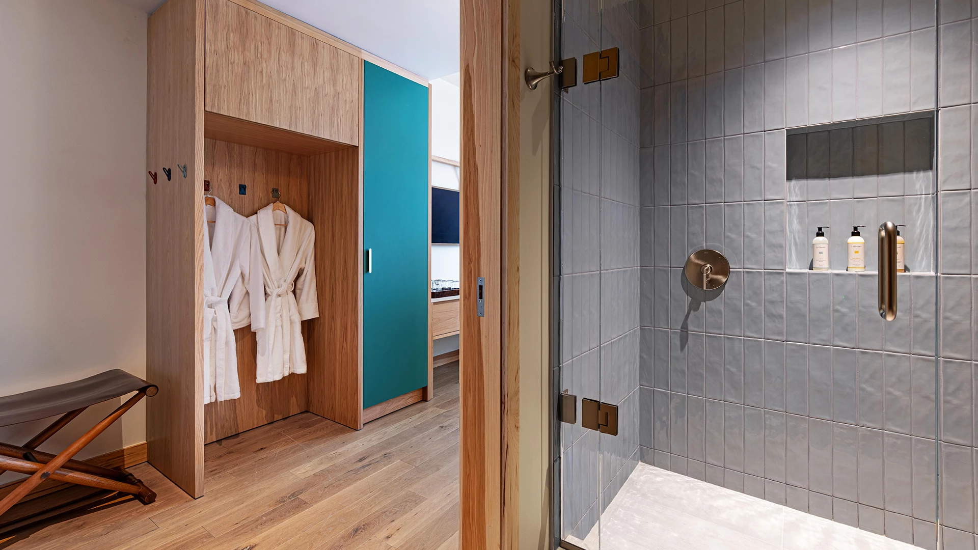 a bathroom with white bathrobes and a glass shower