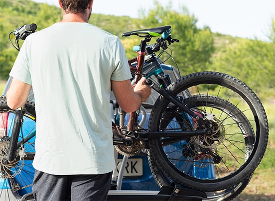 a man holding a bicycle on a car