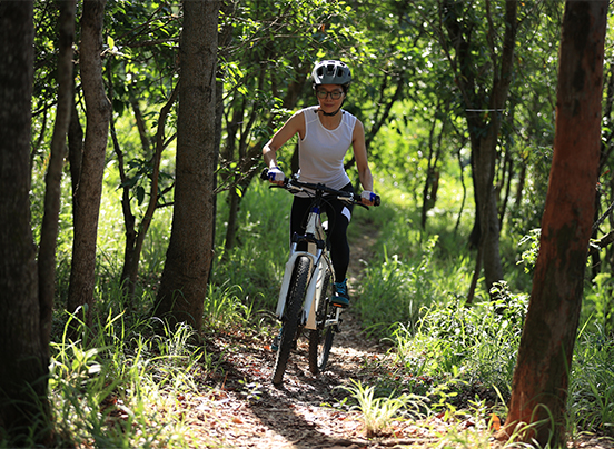 a woman riding a bike through the woods