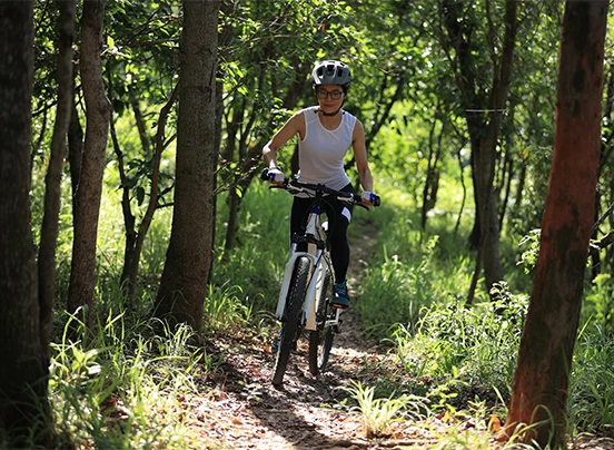 a woman riding a bike through the woods