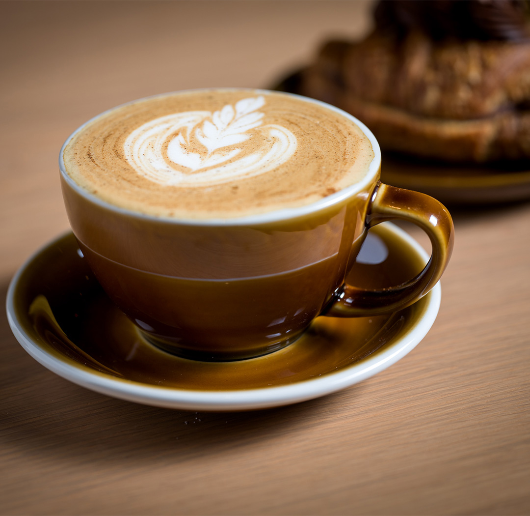 a cup of coffee with a leaf design on top of it