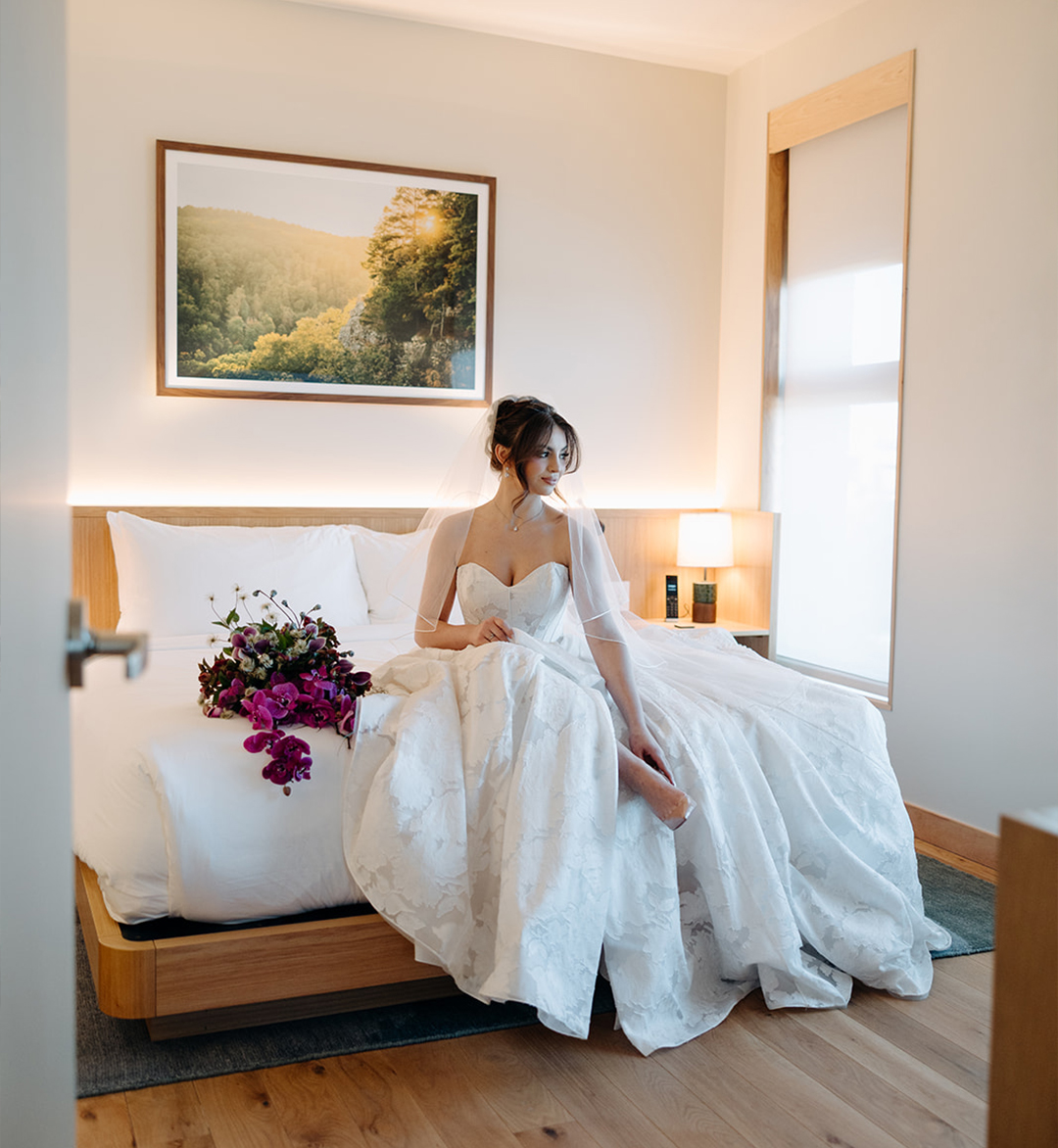 a woman in a wedding dress sitting on a bed