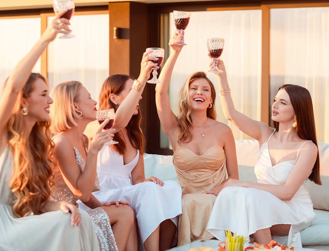a group of women sitting on a couch holding wine glasses