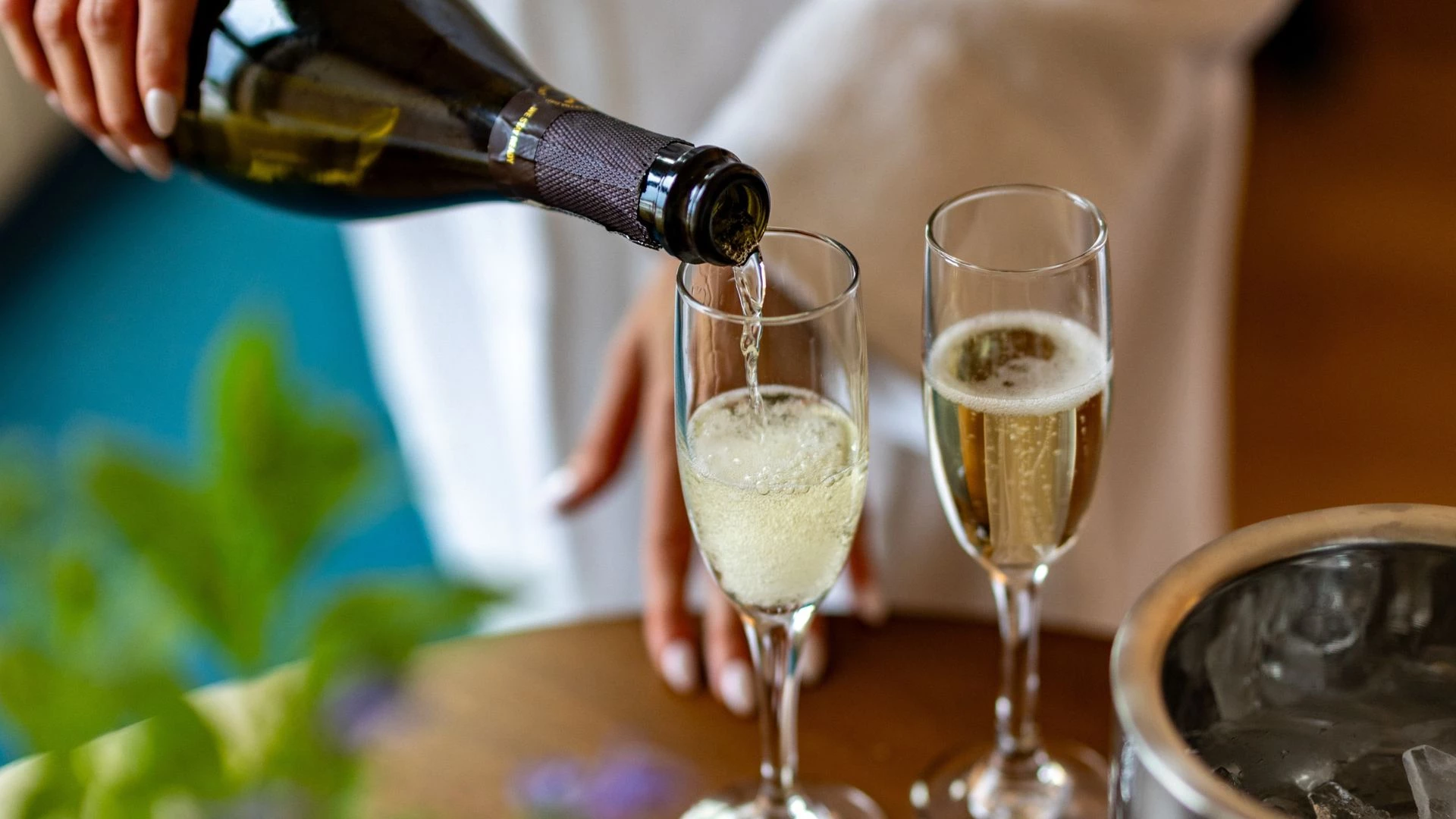 a person pouring champagne into two glasses