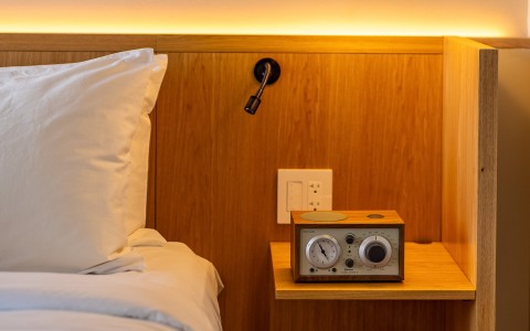 a clock on a table next to a bed