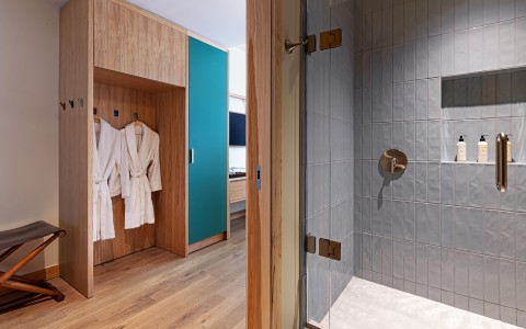 a bathroom with white bathrobes and a glass shower