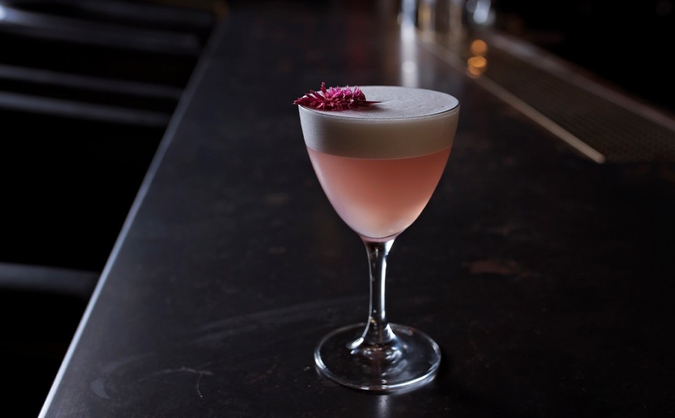 a glass with pink liquid and a flower on top