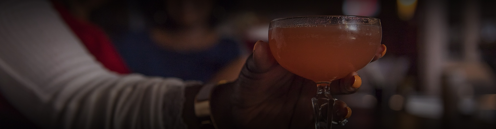 a hand holding a glass of orange liquid