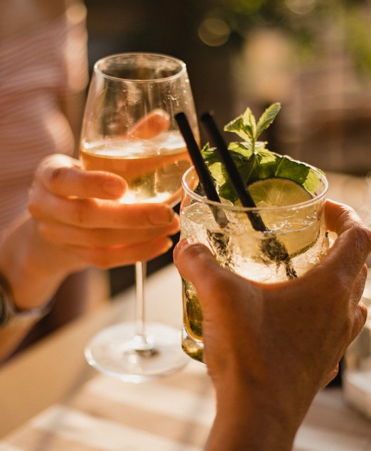 Two people toasting with a mojito and a glass of wine