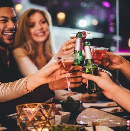 A group of friends toasting with beer and cocktails and having a good time