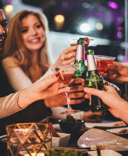 A group of friends toasting with beer and cocktails and having a good time