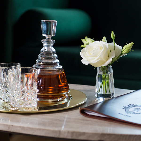 bottle of brandy and glasses on table with flowers