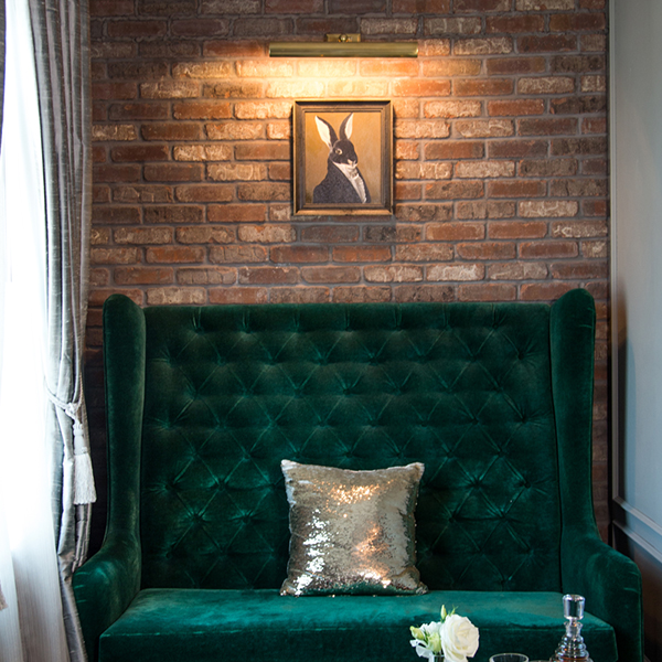Green sofa with picture of rabbit above it