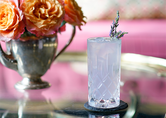 a glass of liquid with a flower on top of it