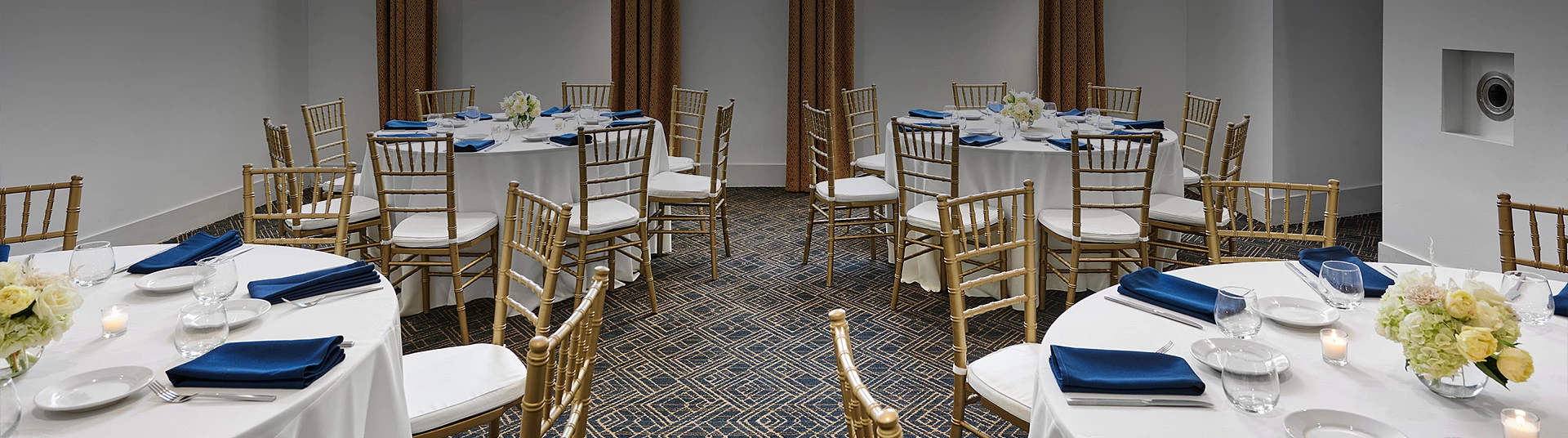 a room with round tables and gold chairs