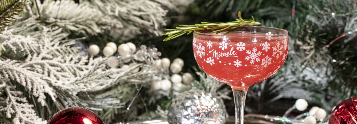 a glass of red liquid with a branch of rosemary on top