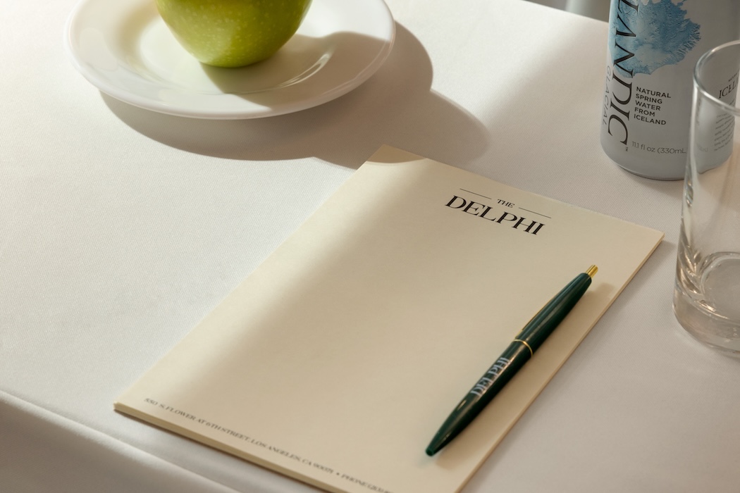 a pen on a paper next to a plate of apple