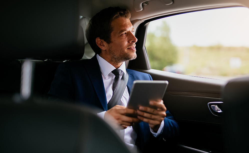 a man in a suit holding a tablet in a car