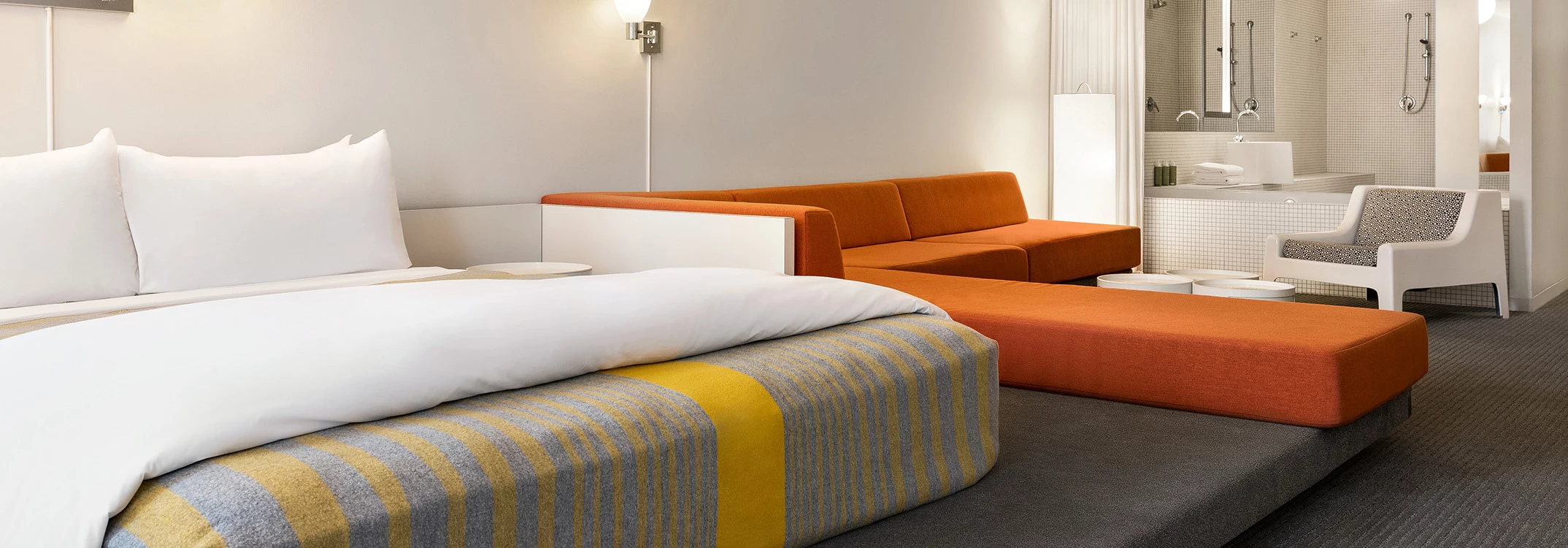 A hotel room with a bed, sofa, and bathroom in the background.