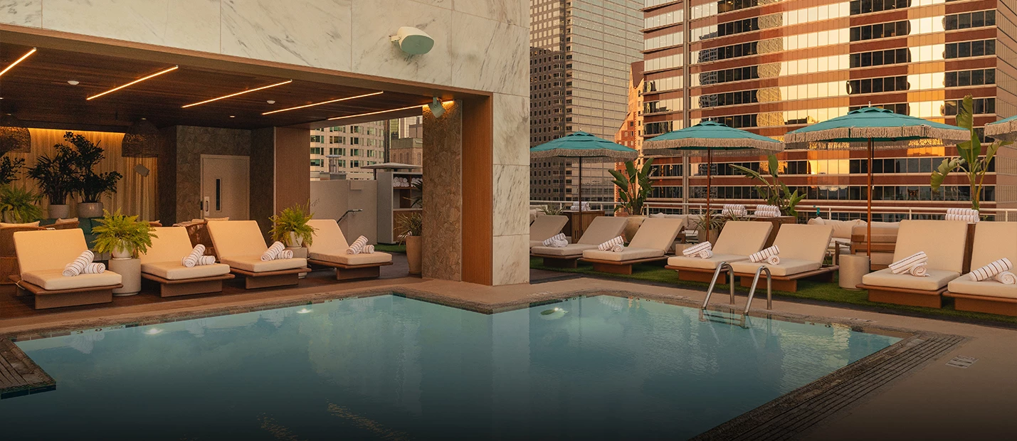 a pool with lounge chairs and umbrellas on a rooftop
