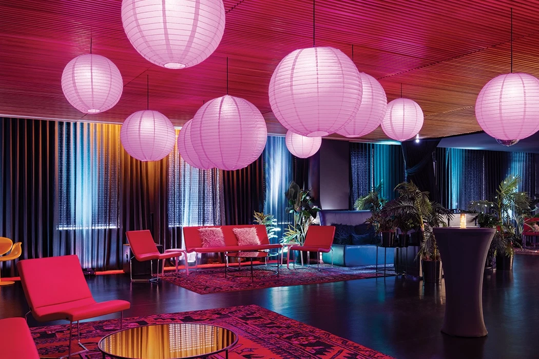 A modern lobby with red accents, paper lanterns, and plants.