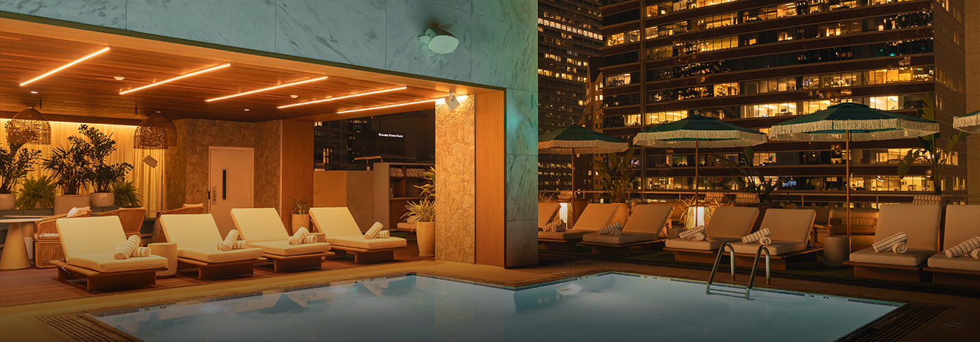 a pool with lounge chairs and umbrellas in front of a building