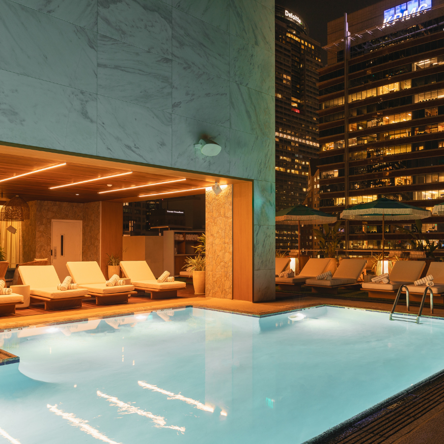 a pool with lounge chairs and umbrellas in front of a building