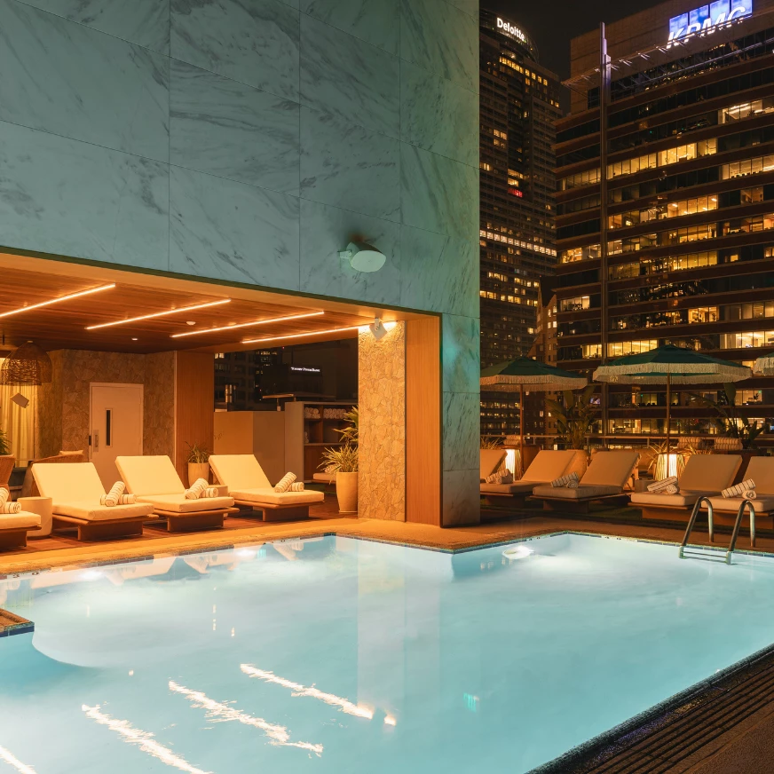 a pool with lounge chairs and umbrellas in front of a building