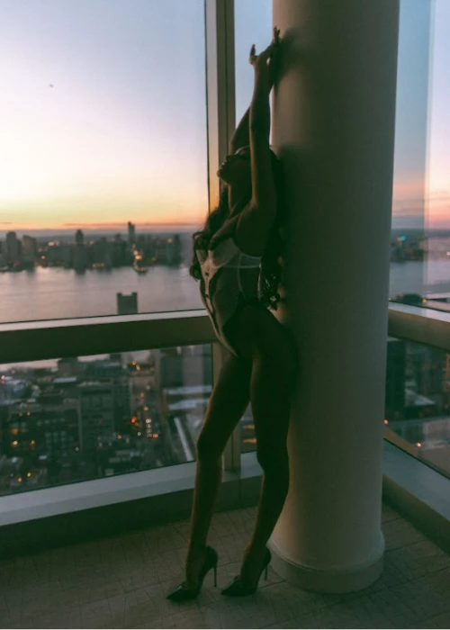 a person in a tight green dress leaning against a window