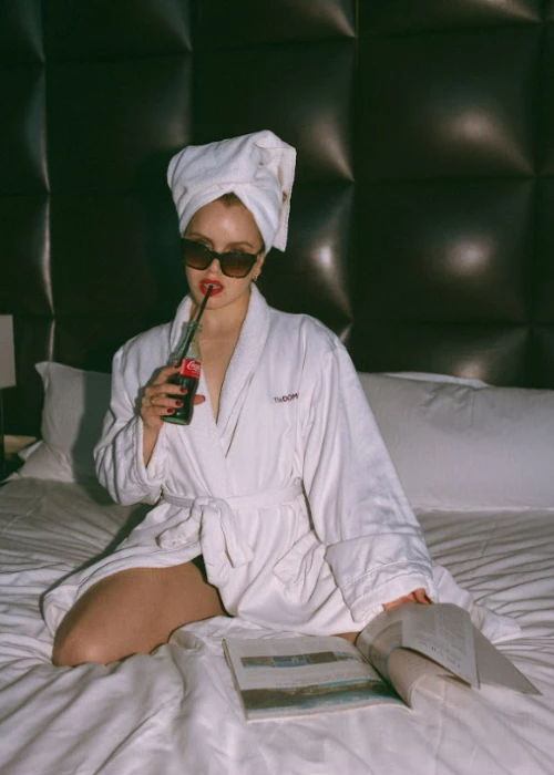 a person wearing a white robe and sunglasses holding a bottle of alcohol