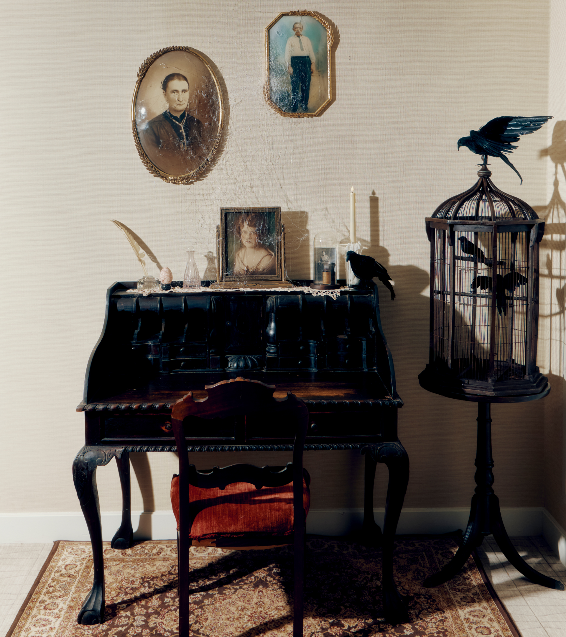 a desk with a bird cage and pictures on the wall