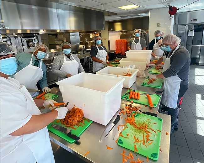 people in a kitchen making meals for someone in need