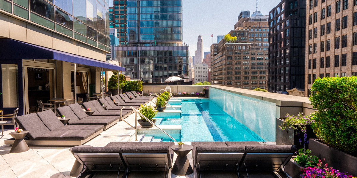 a pool with lounge chairs and a rooftop in the background