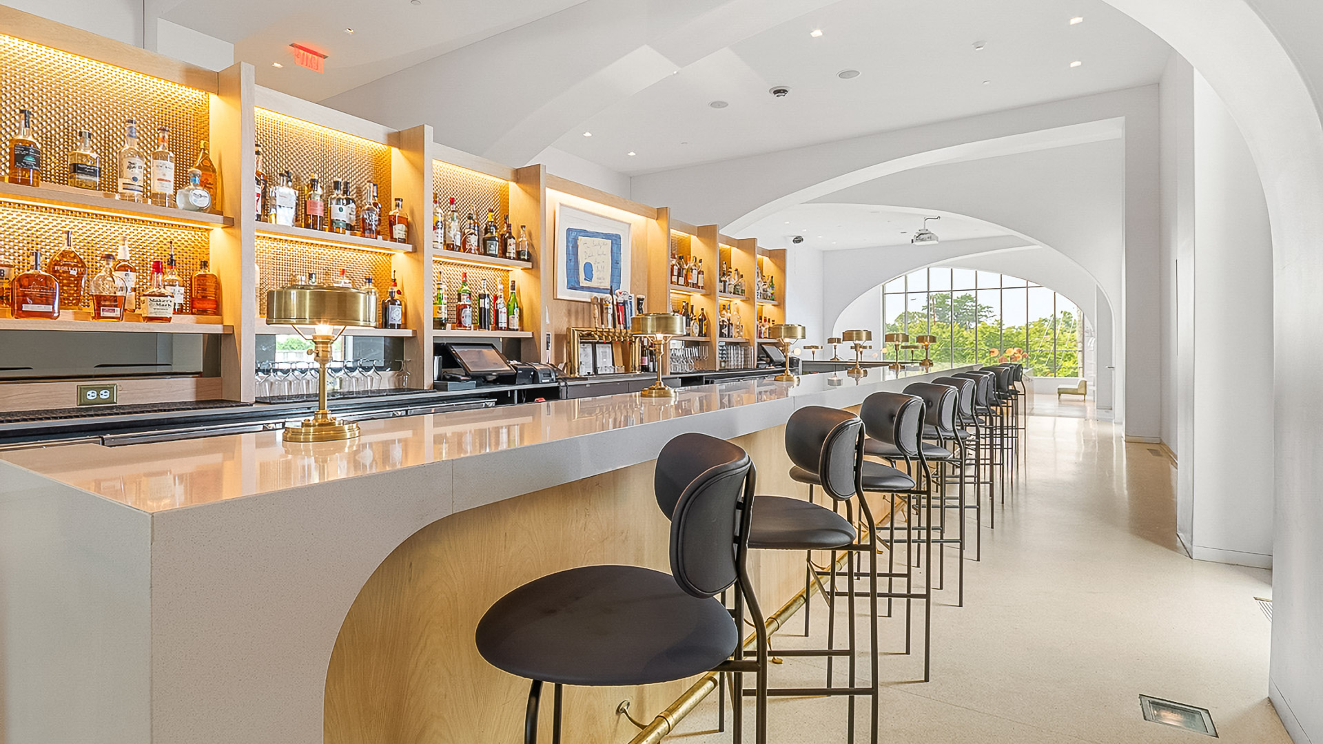 a bar with chairs and a shelf with bottles