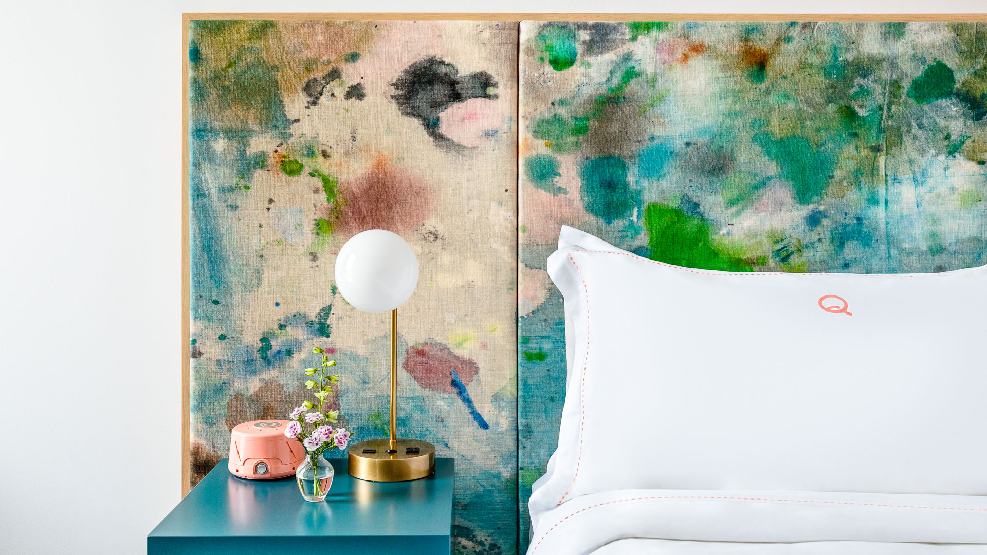 a bed with a white pillow and a lamp on a table