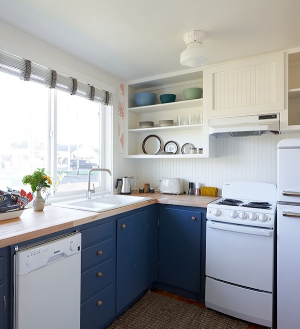 A kitchen with light wood countertops and dark blue cabinets.