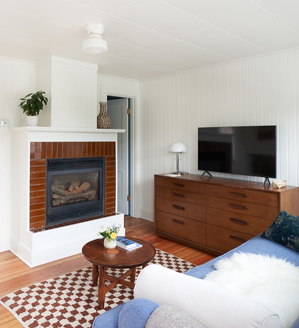 Wooden furniture in a living room with a fireplace and checkered rug.